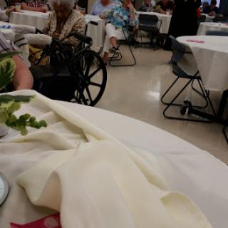 A view of a gathering setting with tables and attendees, including individuals in wheelchairs.