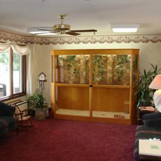 A cozy waiting room featuring a large fish tank and comfortable seating.