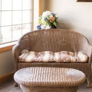 A cozy sitting area featuring wicker furniture and a floral arrangement by the window.