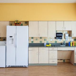 A tidy kitchen with beige cabinets, a white refrigerator, and various cleaning supplies on the countertop.
