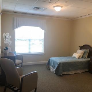 A minimalist bedroom with a single bed, chair, and large window.