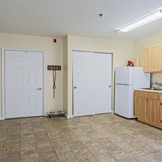 A kitchen area with a refrigerator, wooden cabinets, and a tile floor.