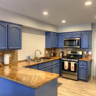 A modern kitchen with blue cabinets and wooden countertops.