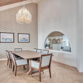 A modern dining room featuring a wooden table, elegant chairs, a stylish chandelier, and decorative wall art.