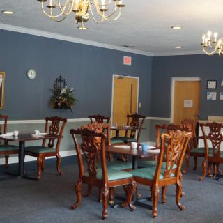 An elegantly furnished dining room with wooden chairs, tables, and chandeliers.