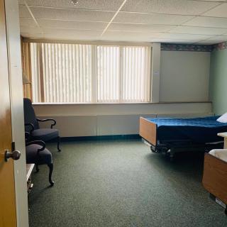 A simple room with a bed, chair, and window.