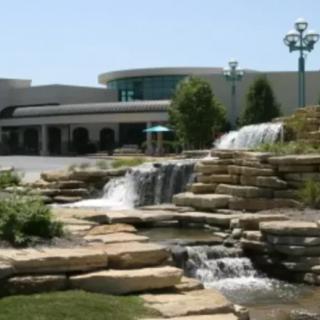 A modern building surrounded by landscaped waterfalls and rock formations.