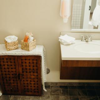 A cozy bathroom with a wooden cabinet, baskets of towels, and a modern sink.
