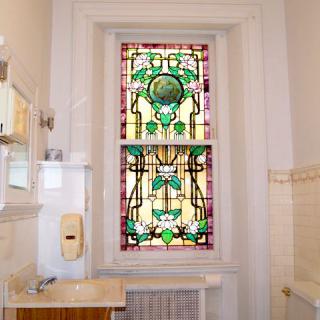 A beautifully designed stained glass window in a bright bathroom setting.