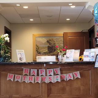 A reception area beautifully decorated for Mother's Day, featuring flowers and a festive banner.