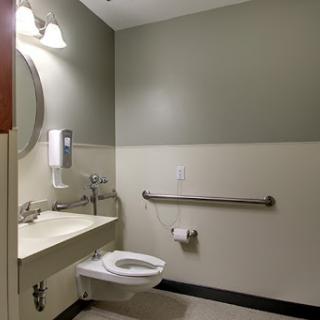 A clean and accessible restroom featuring a toilet, sink, and hand dryer.