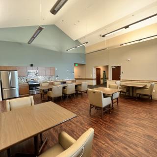 A modern kitchen and dining area with tables, chairs, and a wooden floor.
