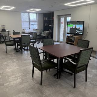 A spacious community dining area with multiple tables and chairs, featuring a television for entertainment.