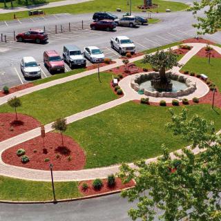 A landscaped area with pathways and a central fountain surrounded by a parking lot.