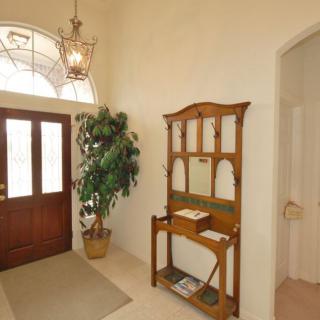 A warmly lit entryway featuring a wooden table and a potted plant next to the front door.