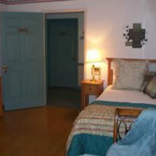 A cozy bedroom with a bed, nightstand, and warm lighting.