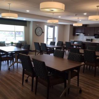 A modern dining room with multiple tables and chairs, well-lit by ceiling fixtures.