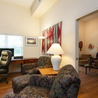 A cozy living room featuring comfortable seating, a lamp, and decorative artwork.