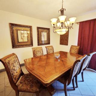 A well-appointed dining room with a wooden table and upholstered chairs beneath a decorative chandelier.