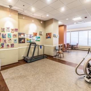 A fitness room with exercise equipment and colorful artwork on the walls.