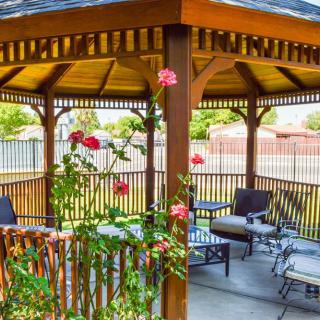 A cozy gazebo with comfortable seating surrounded by a garden of vibrant flowers.