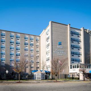 A large hospital building with multiple windows under a clear blue sky.