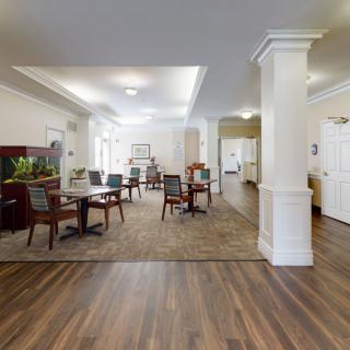A spacious and well-lit dining area with wooden flooring and neatly arranged tables and chairs.