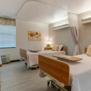 A well-lit hospital room with two patient beds and a clean, organized interior.