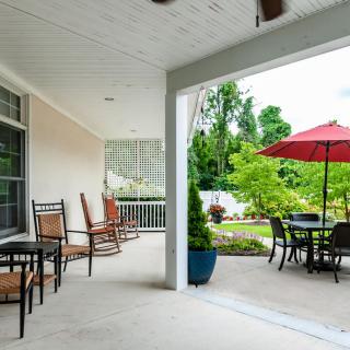 A cozy patio area with outdoor seating, tables, and a view of the garden.