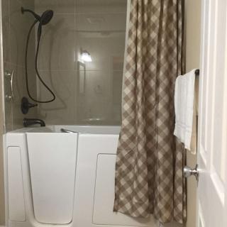 A bathroom featuring a walk-in bathtub with a shower curtain and a towel hanging on the door.