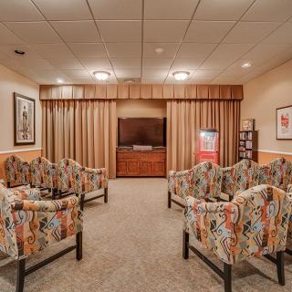 A cozy waiting room featuring patterned chairs, a television, and framed artwork.