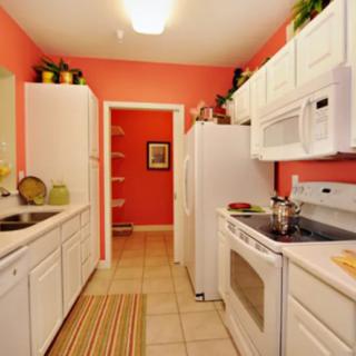 A modern kitchen with white cabinetry and vibrant red walls.