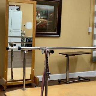 A therapy room equipped with parallel bars and a mirror for rehabilitation exercises.
