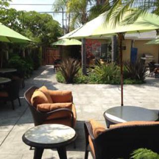 A sunny patio with comfortable garden furniture and large umbrellas providing shade.