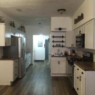 Modern kitchen with white cabinets and hardwood flooring.