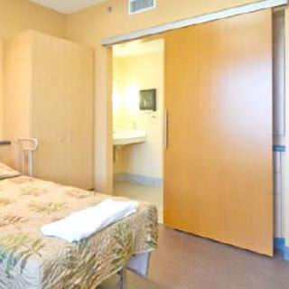 A modern hospital room with a single bed, featuring bright lighting and minimalist design.