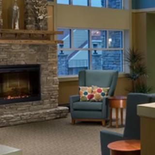 A cozy living room with a stone fireplace and an armchair near a window.