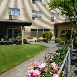 A well-maintained garden with colorful flowers in front of a multi-story building.