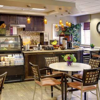 A cozy cafe interior featuring a seating area with tables and chairs, a coffee counter, and warm decor.