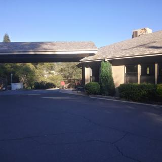 A building with a covered driveway and surrounding trees under a clear blue sky.