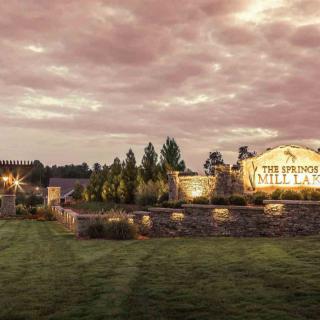 Scenic view of a park entrance at sunset with illuminated signage and landscaped surroundings.