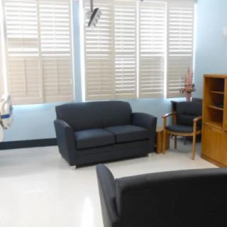 A waiting room with sofas, chairs, and window blinds.