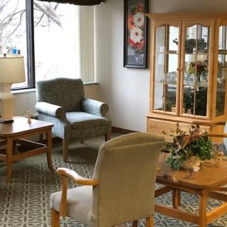 A cozy living room with armchairs, a coffee table, display cabinet, and decor.