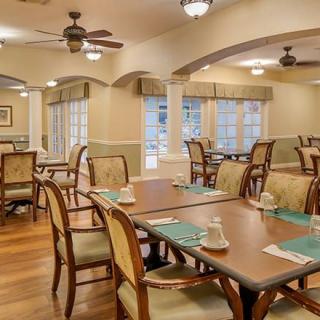 A tastefully decorated dining room with wooden tables and chairs, featuring elegant lighting and large windows.