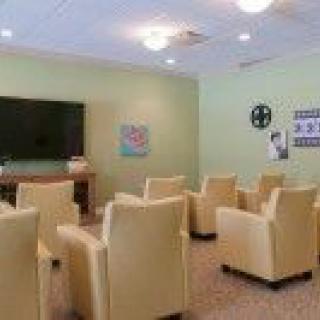 A comfortable seating area with lounge chairs facing a television in a softly lit room.