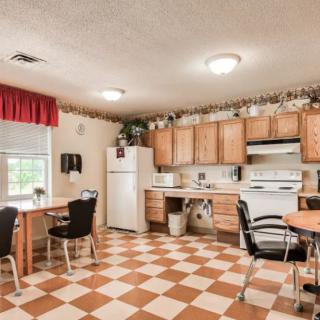 A cozy kitchen with a checkerboard floor, wooden cabinets, and a dining area.