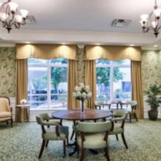 A well-lit living room with a round table and chairs, decorated with elegant curtains and chandeliers.