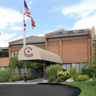 The entrance of a brick building featuring an awning and American flags.