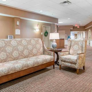 A cozy lobby area featuring a patterned sofa and chair with a lamp on a side table.