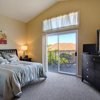 A cozy bedroom with modern decor and a sliding glass door leading to a balcony with scenic views.